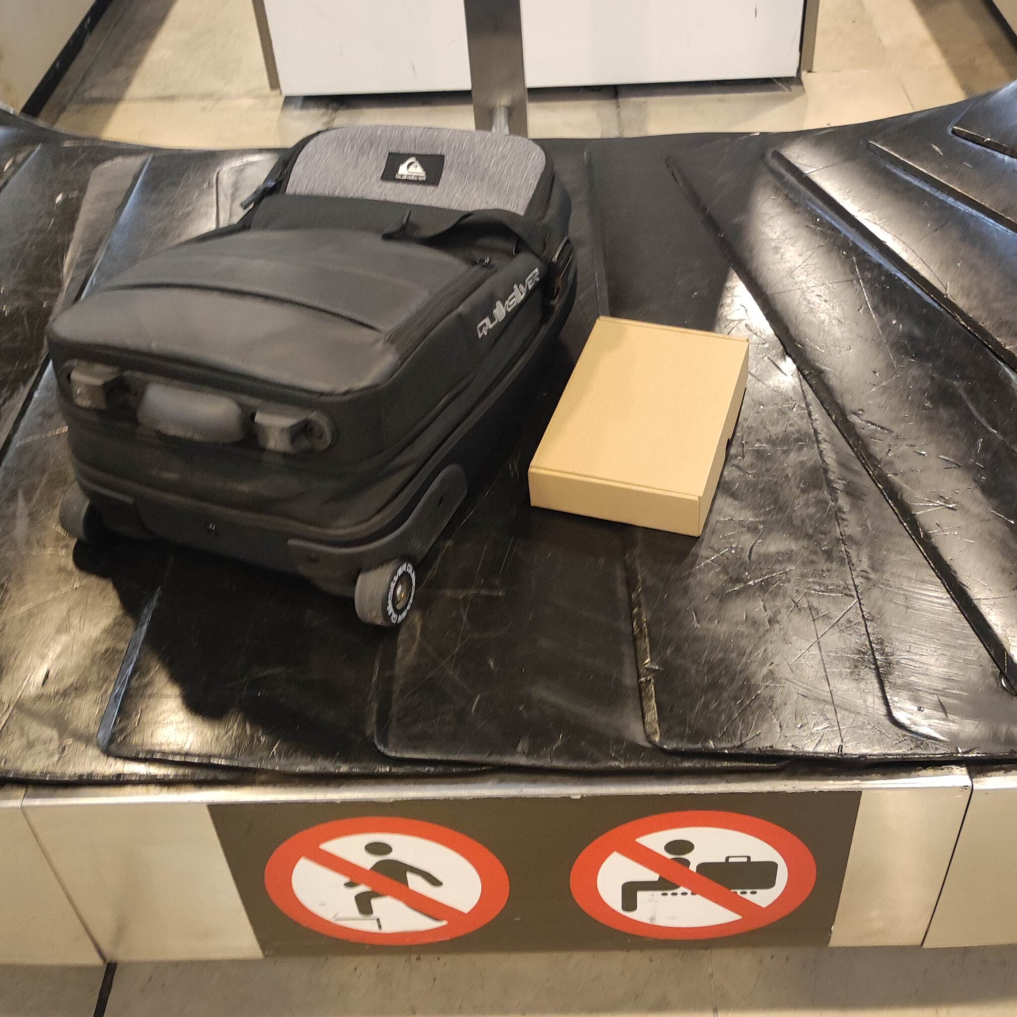 Eine Tasche und eine Kiste auf einem Transportband am Flughafen